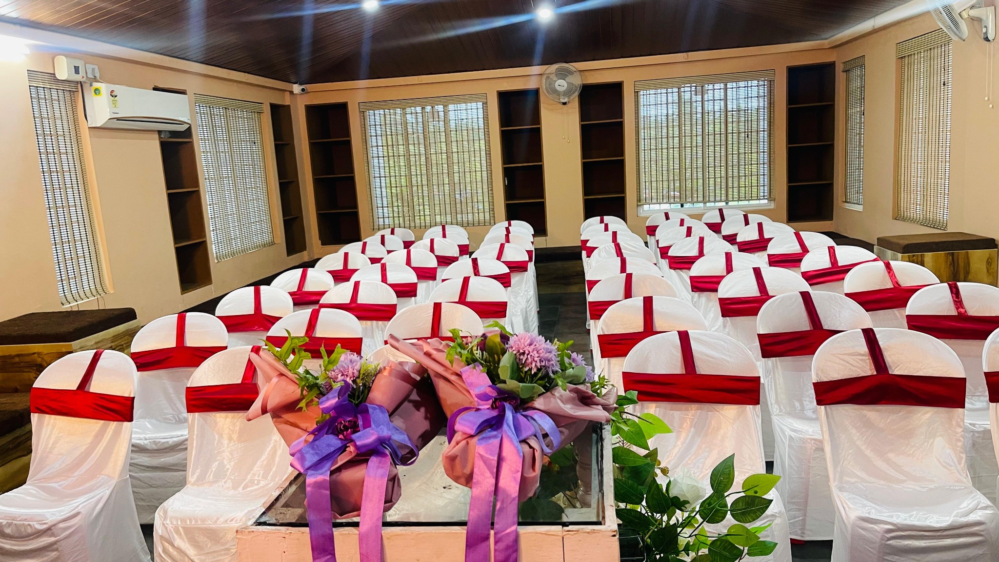 Indoor event hall with white chairs, red sashes and a wood ceiling at Avanti Castello